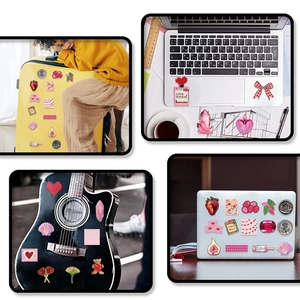 Pink Y2K girlhood stickers decorating a yellow suitcase, laptop and black guitar
