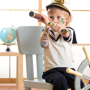 Close-up of 2025 graduation temporary tattoos on a boy's arm featuring hats and badges
