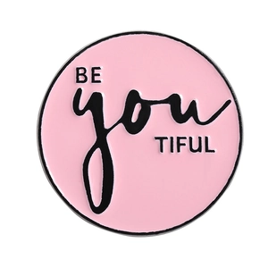 Épingle en émail rose avec typographie créative Be you TIFUL sur un fond blanc pur