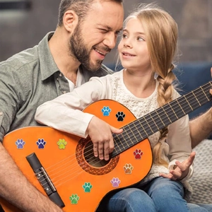 Gros plan d'autocollants colorés en forme de patte avec paillettes sur une guitare