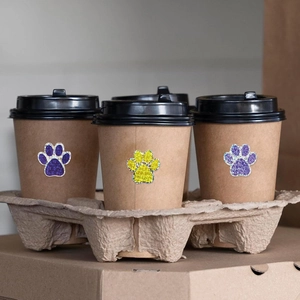 Autocollants de pattes pailletés décorant un gobelet à café en papier kraft recyclé