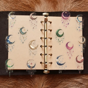 Detailed view of dreamy galaxy moon stickers with stars and gems on vintage journal