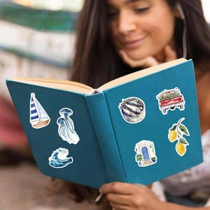 Aesthetic blue coast waterproof stickers applied on a notebook cover in an outdoor setting