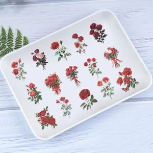 Detail showing vintage red rose PET stickers with hand-drawn floral patterns on blue wood