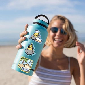 Adesivi di cacatua su una borraccia blu opaca con uno sfondo di spiaggia estiva