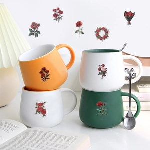 Close-up of vintage red rose ceramic mugs with a heart-shaped silver metal stirring spoon