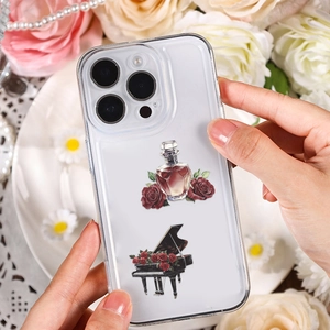 Transparent iPhone case with vintage rose, perfume, and piano illustrations held by hand