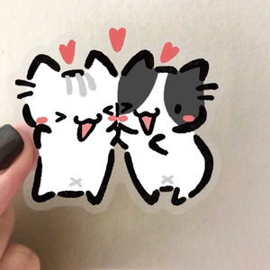 Main tenant deux autocollants de chats mignons dessinés à la main en PET transparent