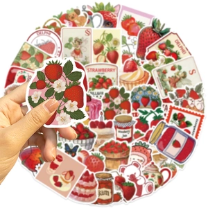 Close-up of hand holding a cute strawberry sticker from the colorful decorative DIY set