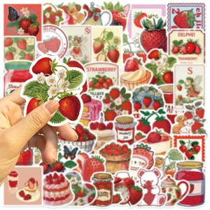 Close-up of hand holding a waterproof cartoon strawberry sticker for DIY laptops and guitars