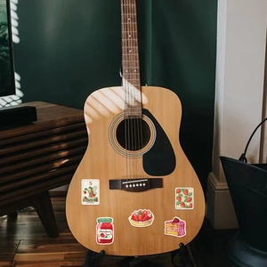 Detail of waterproof strawberry theme stickers applied on a wooden acoustic guitar