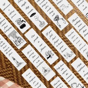 Black and white minimalist bookmarks with inspirational quotes on woven mat background
