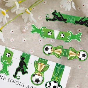 Dettaglio di segnalibri magnetici a tema calcio con disegni di campi e trofei dorati
