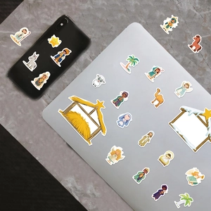 Cartoon Nativity stickers on a laptop and phone, featuring Mary, Joseph, and baby Jesus