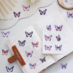 Détail de stickers papillons en PET violet avec textures d'ailes sur pages de livre