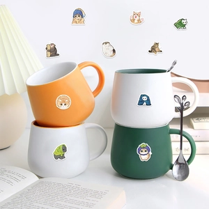 Detail of cartoon cat stickers on desktop with ceramic mugs and vintage book background