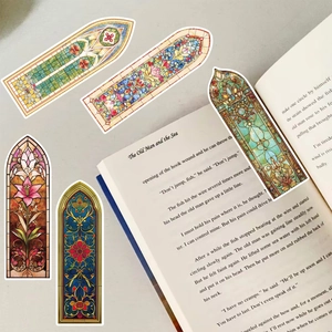 Macro shot of 5 gothic arch window bookmarks with stained glass patterns on a book
