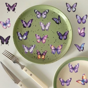 Vue à plat d'autocollants papillon en PET violet imperméable sur une assiette décorative