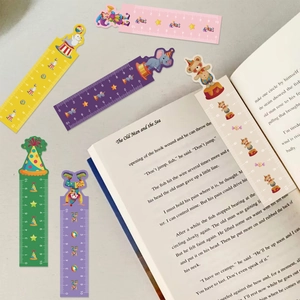 Kleurrijke papieren bladwijzers met een circusmotief en 10 cm liniaal op een boek