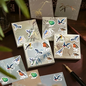 Detailed bird stickers on a bamboo journal with elegant stationery and wooden tray