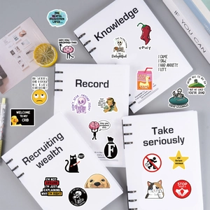 Detail of waterproof funny prank meme stickers applied on white spiral notebooks