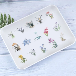 Detailed view of 50 floral orchid PET stickers on a white tray for journaling