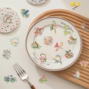 Detalle de pegatinas decorativas de PET con aves y flores en una bandeja de madera
