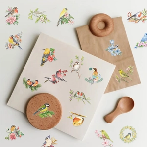 Detalle macro de pegatinas de pájaros en acuarela en un diario y accesorios de madera