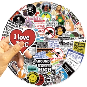 Close-up of hand holding waterproof prank meme stickers for DIY laptop and guitar decor