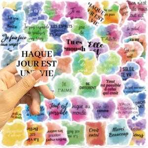 Close-up of waterproof watercolor French quote stickers for laptop and guitar decoration