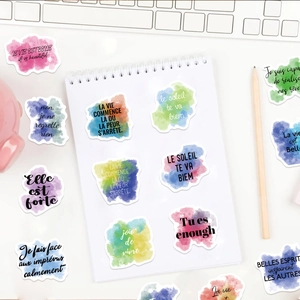 French watercolor motivational stickers on a white notebook with lifestyle props
