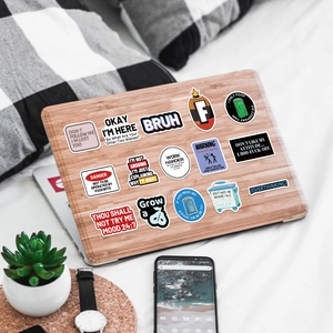 Funny waterproof prank meme stickers on a wooden laptop cover with office accessories