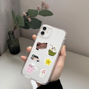 Close-up of a clear phone case with cute bear and travel stickers on a smartphone