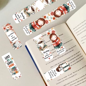 Close-up of hand-drawn paper bookmarks with floral and reading motifs on an open book