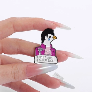 Macro shot of purple enamel pin featuring Prince inspired bird and music lyrics