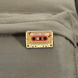 Nahaufnahme der Retro-Emaille-Brosche in Kassettenform mit CHILL OUT-Text auf Stoff