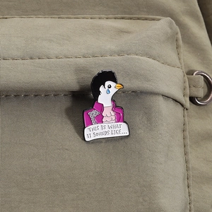 Detail of the Prince-inspired dove enamel pin pinned on a green canvas bag strap