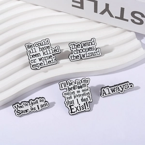 Five minimalist enamel pins with wizard movie quotes on white corrugated display