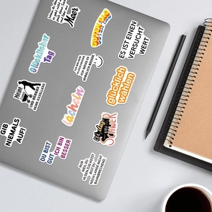 Close-up of German motivational stickers applied on a laptop with office accessories