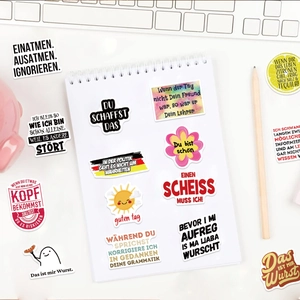 Close-up of German motivational stickers on a notebook with laptop and pencils