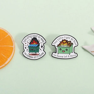 Dumpster fire enamel pins with humorous quotes 'This little light of mine' on green background