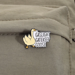 Detail view of Gaslight Gatekeep Goose enamel pin on a dark green canvas backpack