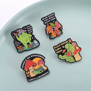 Lot de pins émaillés grenouille et champignon avec citations sur une assiette en céramique