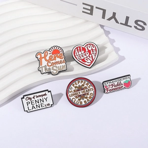 Set of 5 Beatles enamel pins featuring classic song lyrics on a white display board