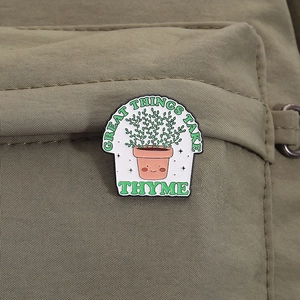 Cute cactus enamel pin with 'Great Things Take Thyme' quote on green fabric texture