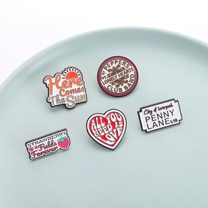 The Beatles song title enamel pins set in colorful geometric shapes on blue ceramic plate