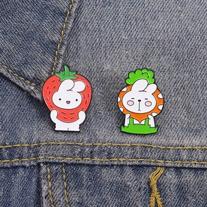 Cartoon rabbit strawberry and carrot enamel pins on dark blue denim fabric texture