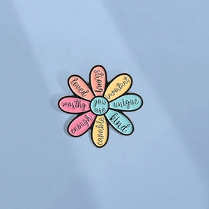 Colorful floral enamel pin with inspirational English words on a light blue background