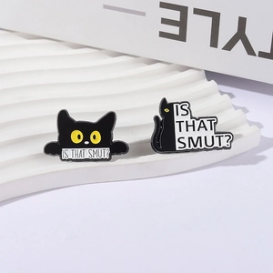 Pair of funny black cat enamel pins with large yellow eyes on a white wavy stand