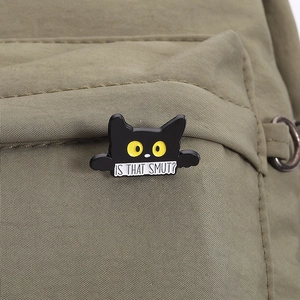 Dettaglio di una spilla in smalto gatto nero con citazione su borsa in tela di canapa